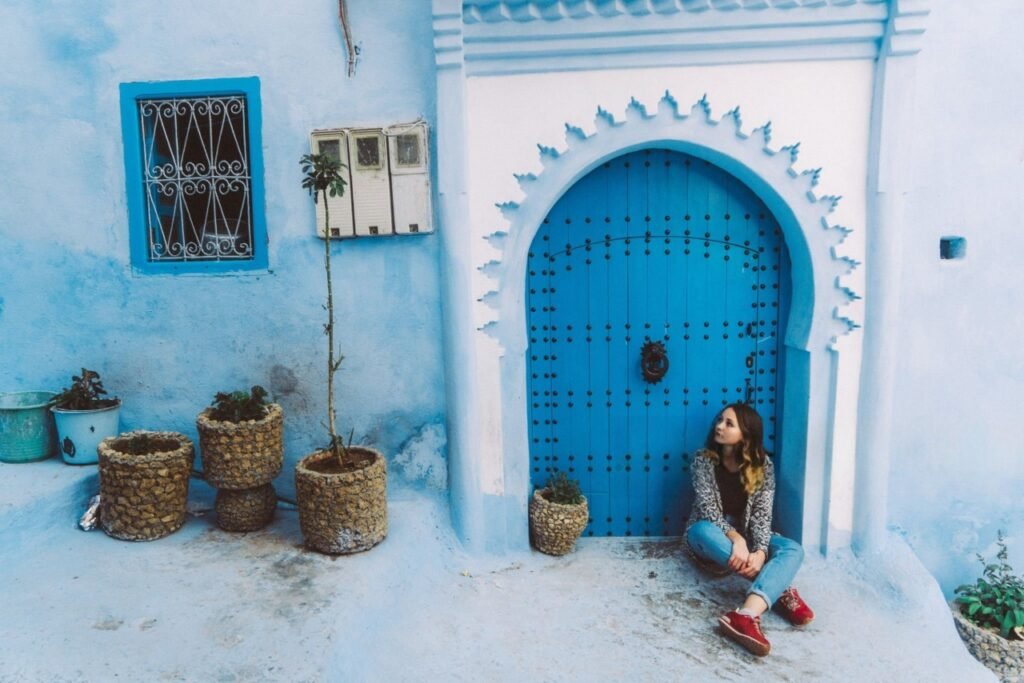 Girl walking through the blue streets of Chefchaouen, Morocco, wearing traditional attire and exploring the medina