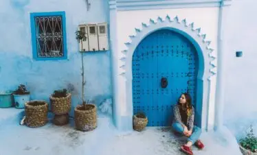Girl walking through the blue streets of Chefchaouen, Morocco, wearing traditional attire and exploring the medina