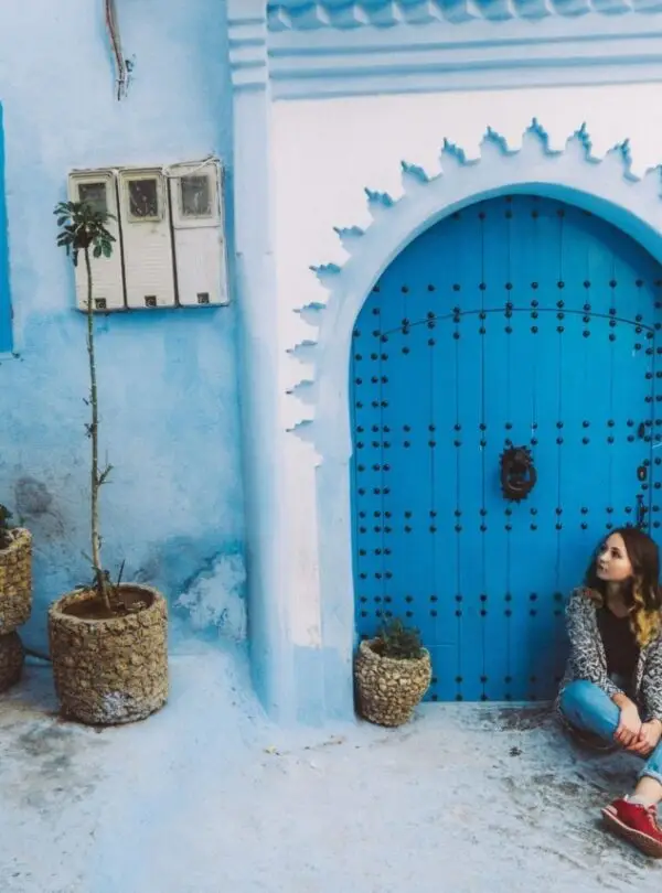 Girl walking through the blue streets of Chefchaouen, Morocco, wearing traditional attire and exploring the medina